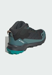 Schwarzer Wanderschuh mit Mesh-Obermaterial, türkisfarbenen Akzenten und grauer Sohle. Verfügt über ein markantes Branding und ein robustes Profil für besseren Halt.