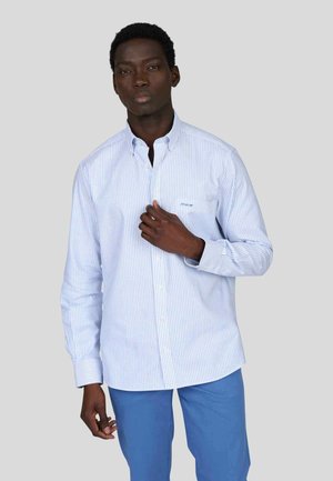 Chemise à manches longues rayée bleu clair et blanche avec un col à boutons, dotée d'une poche poitrine et d'un design de poignet standard.