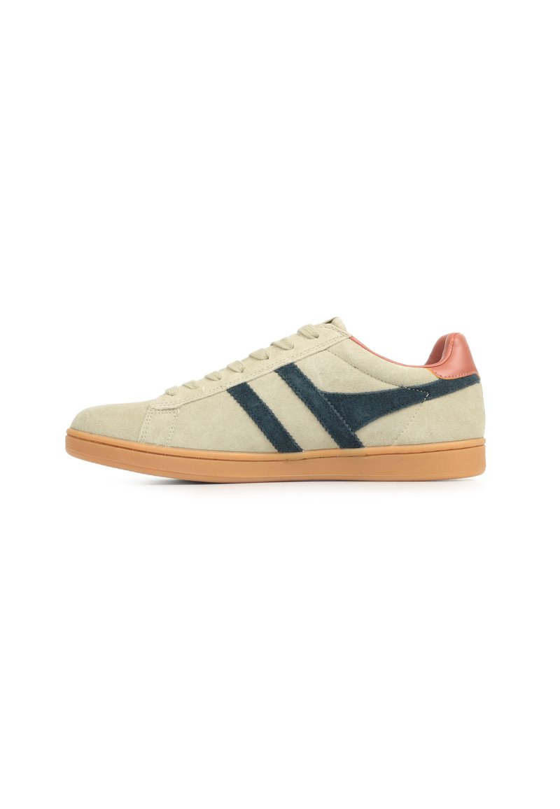 Suède sneakers in lichtbeige met donkerblauwe diagonale strepen, bruine accenten bij de hak en een tan rubberen zool. Klassiek veterschoenontwerp.