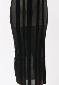 Gonna a maglia a righe verticali nera e grigio scuro con texture a coste, silhouette aderente e pannelli semitrasparenti alternati su uno sfondo bianco.