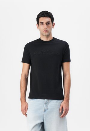 Svart t-skjorte med korte ermer som har hevet tekst "KARL LAGERFELD" på forsiden, laget av mykt stoff med et klassisk rundhalsdesign.