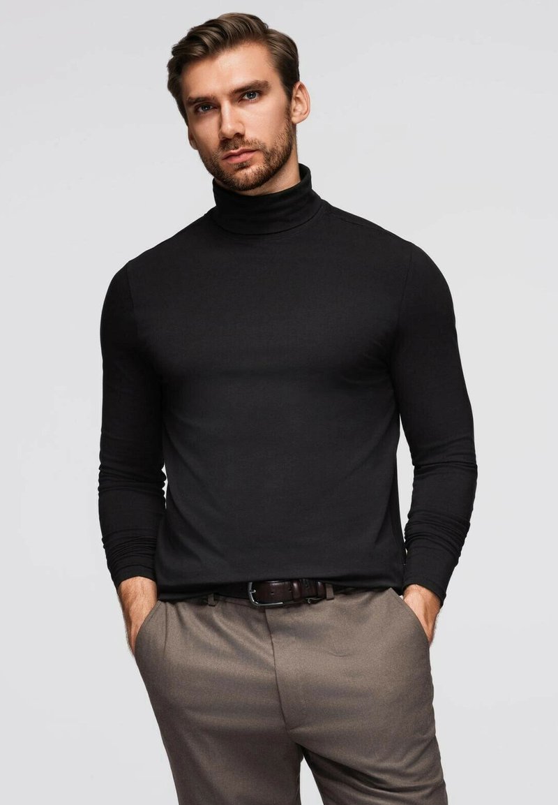 Schwarzes Rollkragenhemd mit langen Ärmeln, figurbetontes Design, kombiniert mit hellbraunen Hosen und einem dunklen Gürtel. Glatte Textur, minimale Details.