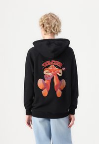 Czarna bluza z kapturem z wyrazistą grafiką postaci grającej na gitarze. Dodatki obejmują sznurek w kapturze i ściągacze na rękawach. Luźny krój.