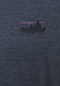 Mörkblå t-shirt med kort ärm gjord av mjukt tyg, med en bergsgraphic i svart och röda samt blå linjer ovanför texten "patagonia."