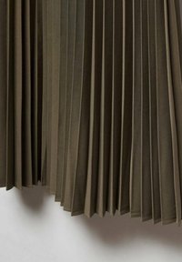 Tissu vert olive plissé avec des plis verticaux espacés uniformément créant un motif texturé et fluide.