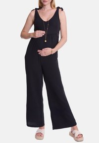 Schwarzer, ärmelloser Jumpsuit aus strukturiertem Stoff, mit gebundenen Schulterträgern, tailliertem Schnitt und weitem Bein.