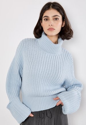 Maglione lavorato a maglia di colore azzurro chiaro con colletto alto a coste, maniche larghe e un motivo testurizzato. Presenta un design corto con una vestibilità rilassata.