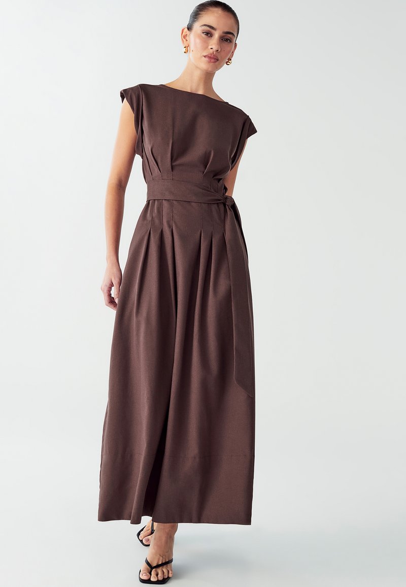 Hnědé maxi šaty bez rukávů s páskem v pase, skladbovým designem a rovnou siluetou. Měkká tkanina s hladkým povrchem.