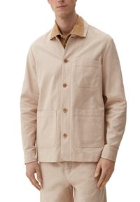 Jasno beżowa kurtka z teksturowanej tkaniny z kontrastowym brązowym kołnierzem, z dwoma przednimi kieszeniami i drewnianymi guzikami, w komplecie ze spodniami w tym samym odcieniu.