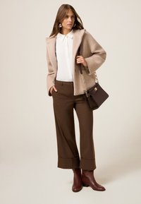 Beige gestructureerde wollen blazer, witte blouse, bruin geruite wijde broek, en bordeauxrode enkellaarsjes, gecombineerd met een bruine handtas.