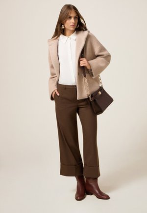 Beige gestructureerde wollen blazer, witte blouse, bruin geruite wijde broek, en bordeauxrode enkellaarsjes, gecombineerd met een bruine handtas.