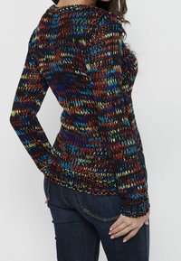 Meer kleurige gebreide trui met zwart, rood, blauw en geel garen, met een aansluitend ontwerp en geribbelde manchetten en zoom.