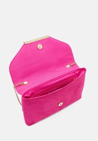Fuksia näppärä laukku kultaisilla yksityiskohdilla, jossa on napsautettava sulku ja sisäinen vetoketjullinen tasku. Avoin muotoilu näyttää sileän vuorauksen.