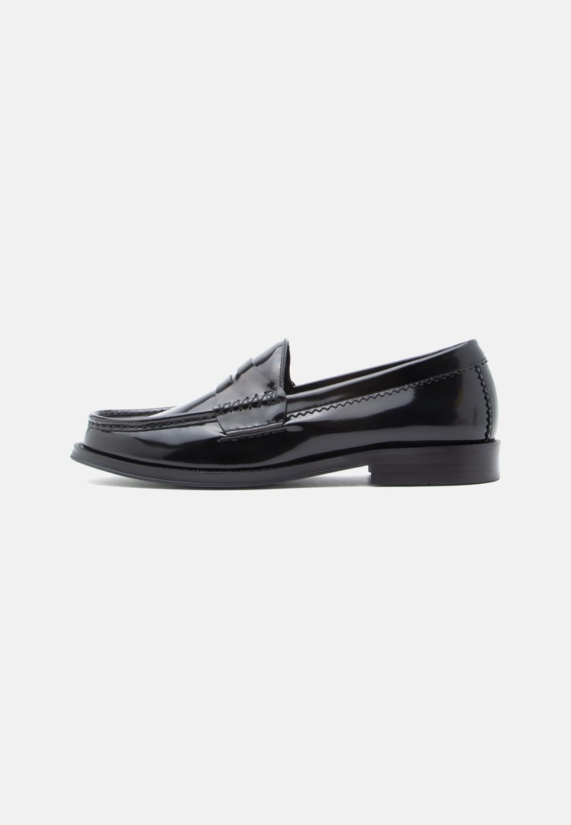 Mocassin en cuir verni noir avec un bout arrondi, des détails cousus et un petit talon empilé. Surface lisse avec un éclat subtil.