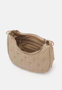 Quilted beige handbag with a rounded shape, zipper closure, diamond pattern, and silver hardware detailing. Interior features a small pocket.