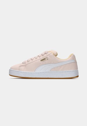 Lichtroze suède Puma sneakers met een witte zool, witte zijstreep en gouden logo tekst aan de buitenkant.