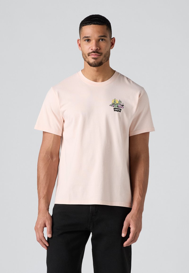 T-shirt di cotone rosa chiaro con un design grafico con accenti verdi e viola, maniche corte e colletto girocollo classico.