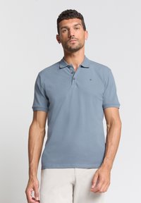 Korte mouwen polo in lichtblauw, gemaakt van zachte katoenstof, met een platte kraag, drie knopen en een subtiele logodetail.