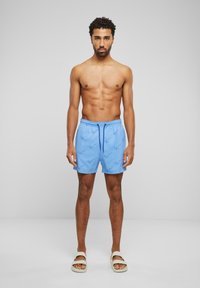 Shorts de bain bleus avec une taille à cordon, présentant un motif subtil de dessins légers bleus à la main. Tissu lisse avec une coupe décontractée.
