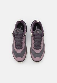 Lila och grå atletiska skor med ett strukturerat meshtyg, kontrasterande snören, en vadderad krage och en robust yttersula.