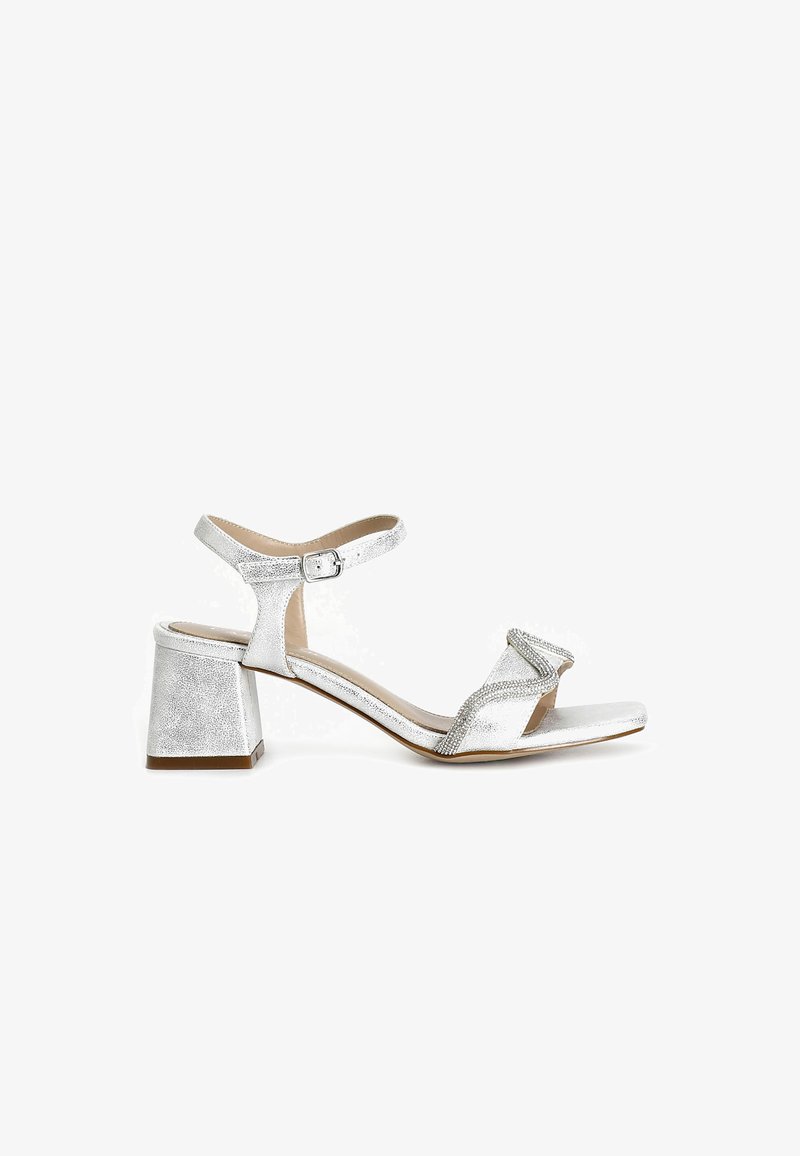 Stříbrná sandál s podpatkem s texturovaným povrchem, otevřenou špičkou, nastavitelným páskem na kotníku a blokovým podpatkem. Obsahuje dekorativní pásek přes špičku.