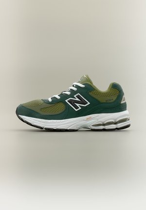 Grüner und dunkelgrüner New Balance Laufschuh mit weißen Schnürsenkeln, weißer und schwarzer Sohle und schwarzem "N"-Logo an der Seite.