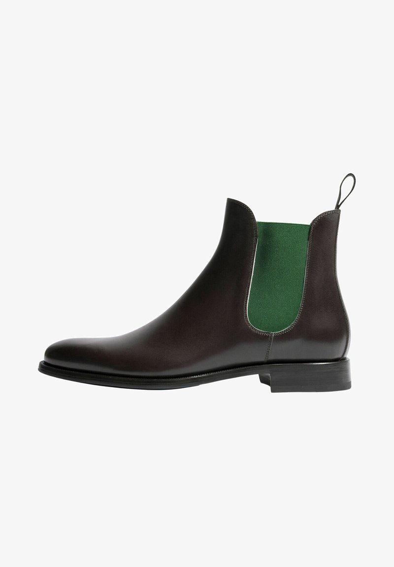 Botín Chelsea de cuero marrón con panel lateral elástico verde, punta redondeada, tirador y suela negra. Diseño elegante y textura suave.