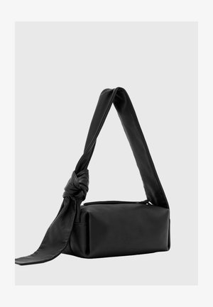 Schwarze rechteckige Lederhandtasche mit breitem Träger, an einer Seite zu einem Knoten gebunden, vor einem schlichten hellen Hintergrund dargestellt.