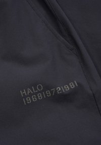 Schwarzer Stoff mit glatter Textur zeigt bedruckten Text: "HALO 196819721981" in einem helleren Farbton. Mit schrägen Nähten zugeschnitten.