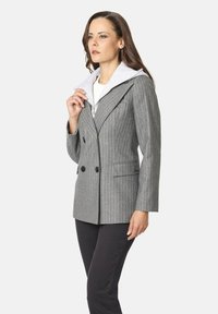 Blazer gris de rayas con botones de doble pecho, solapas con muesca y un forro con capucha de gris claro. Con bolsillos y un corte ajustado.