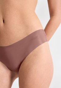 Culotte de bikini seamless en mauve clair avec une texture douce et lisse et un design minimaliste. Présente une fine ceinture avec un logo de marque subtil.