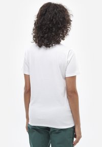 T-shirt blanc à manches courtes avec un col rond et une texture lisse, vu de dos. Aucun motif ni graphique visible.