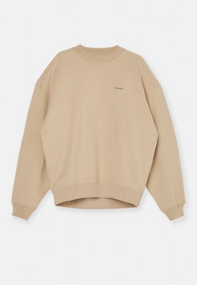 Bézs színű pamut pulóver, kerek nyakkal, esésben lévő vállakkal, széles ujjakal és rövidített szegéllyel. Finom logó a mellkason.