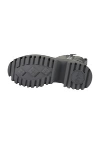 Černá podrážka gumové boty s hlubokými drážkami pro lepší trakci, zaobleným tvarem a kruhovým logem na patě. Texturovaný povrch pro lepší uchopení.