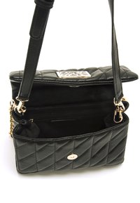 Bolso de mano de cuero negro acolchado con una placa de logo dorada, una cadena y correa de cuero, y un bolsillo interior. Cierre de imán.
