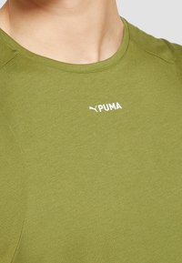 T-shirt de sport vert olive en tissu doux avec un col rond et le logo blanc "PUMA" affiché en évidence sur la poitrine.