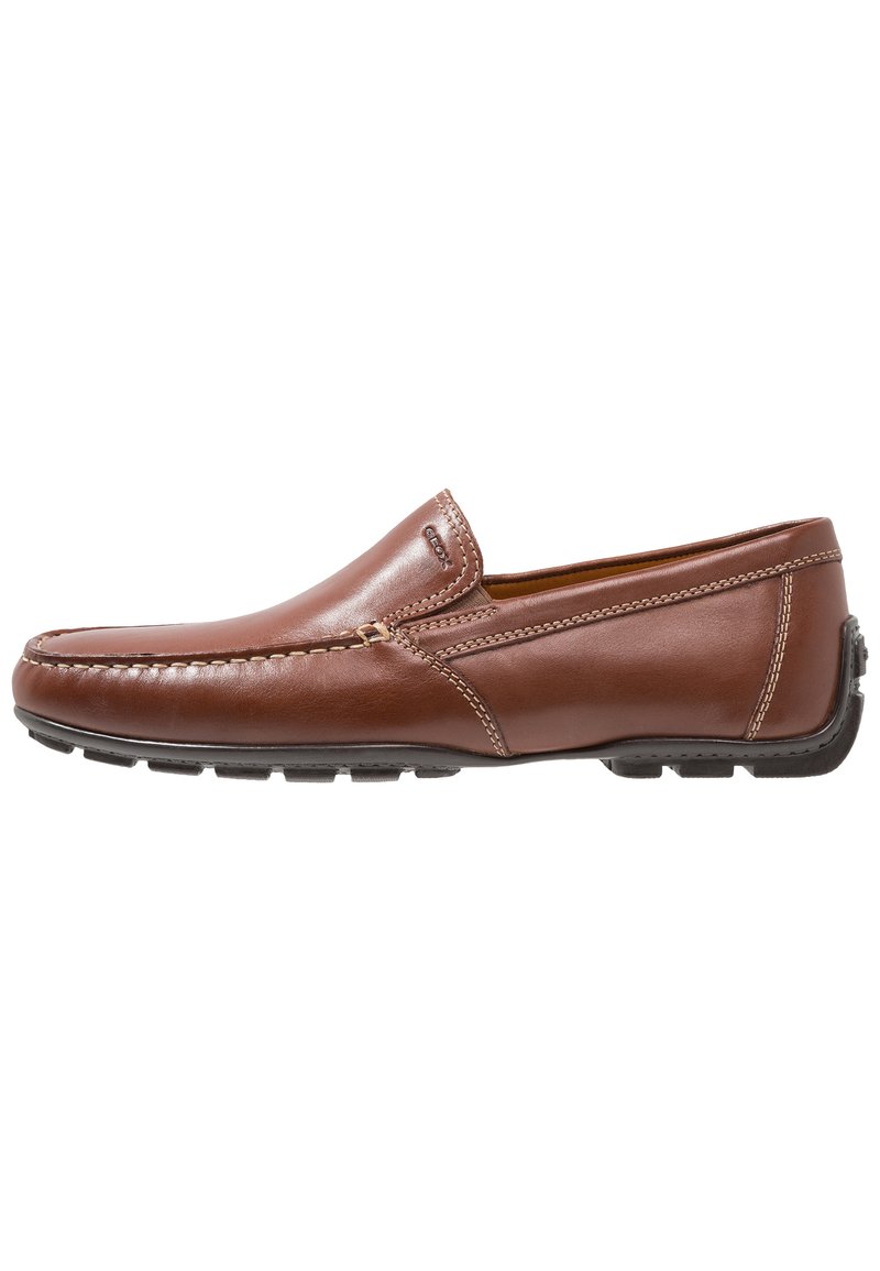 Brun læder slip-on sko med en glat overflade, kontrasterende syninger og en rund tå. Har en robust gummisål med skridsikre detaljer.