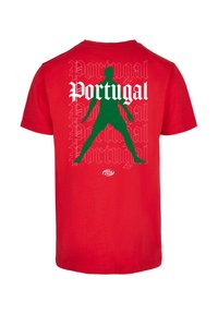 Raudona medvilninė marškinėliai su žalia siluetu ir balto teksto "Portugal" stilizuotu šriftu, kartojančiuosius. Dydžio etiketė apačioje.