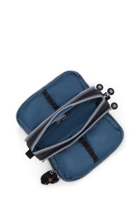 Pochette zippée en nylon bleu foncé avec des accents noirs, comportant deux compartiments et un charm en peluche noire attaché à la fermeture éclair.