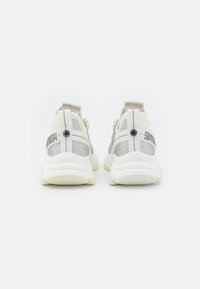 Weiße Sneaker mit metallischen silbernen Akzenten, strukturiertem Mesh-Gewebe und Zugschlaufen. Sie verfügen über eine gepolsterte Sohle und ein Logo auf der Rückseite.