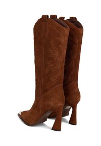 Stivali da cowboy in suede marrone con punta affusolata, tacco di 10 cm e dettagli di cucitura intricati. Dotati di linguette per indossarli facilmente.