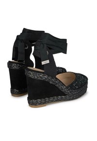 Sandali con zeppa caratterizzati da una tomaia in tessuto intrecciato nero, tacco in finta suede, base tessuta testurizzata e cinturini alla caviglia regolabili in nastro.