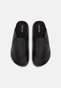 Svarta läderskor utan snörning med en slät yta, rund tå och vadderad insida. Minimalistisk design med en flexibel gummisula.
