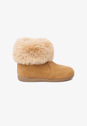 Beiger Wildlederstiefel mit dickem, hellbeigem Kunstpelz-Bündchen. Abgerundete Spitze und flache, strukturierte Gummisohle. Schlichte Nahtverarbeitung entlang der Nähte.