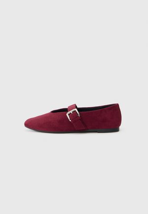 Sapatilha burgundy em camurça, com bico arredondado, design minimalista e uma tira decorativa com fivela no peito do pé.