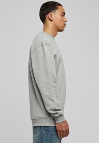 Sudadera gris de algodón, con cuello redondo, mangas largas y puños acanalados. Corte casual con una textura suave.