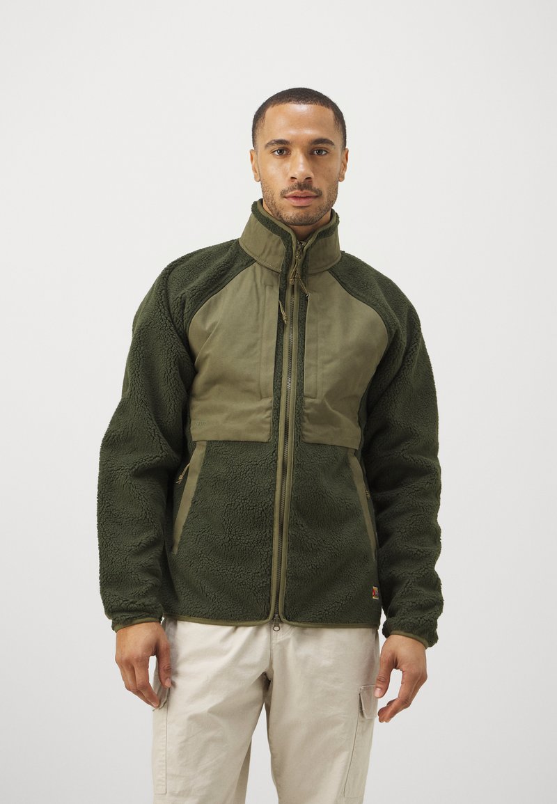 Jachetă de fleece verde, cu un panou frontal și un guler dintr-un material neted contrastant, fermoar complet și material texturat în întregime.