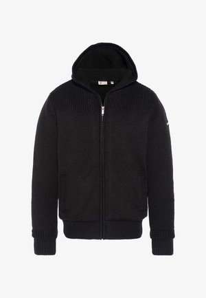 Sudadera negra con cremallera, confeccionada en tela de punto. Presenta un patrón texturizado en los hombros, bolsillos laterales y puños y dobladillo acanalados.