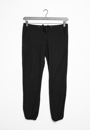 Pantalon de jogging noir à cordon de serrage avec poches latérales et poignets élastiqués, suspendu à un cintre en métal sur un fond blanc.