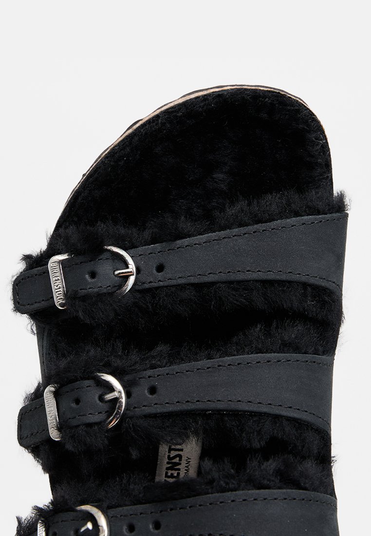 Sandali neri pelosi con tre cinturini regolabili con fibbie argentate, morbido tessuto e soletta imbottita.